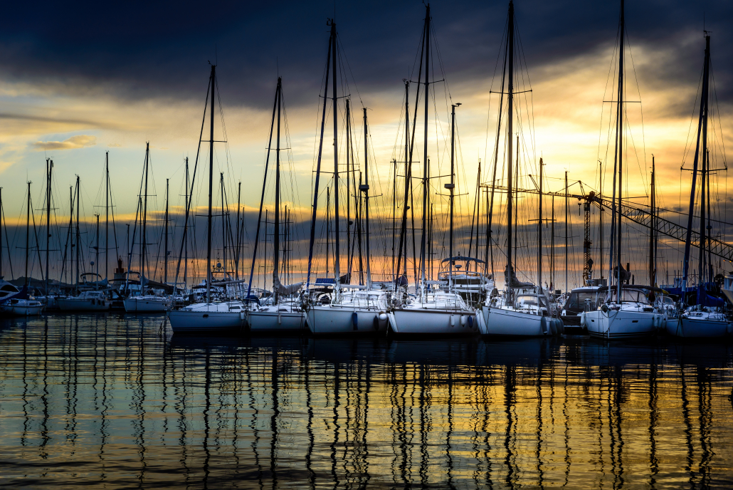 Horizontal shot of modern white yachts parked next to each other in the docks during sunset